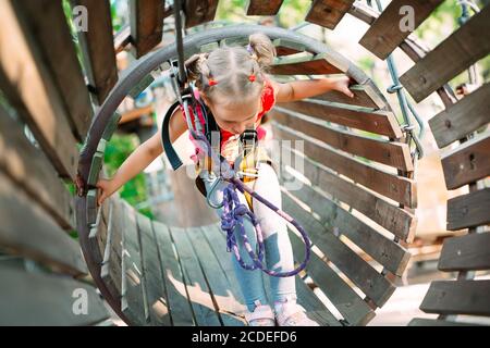 Parcheggio per funi. Il bambino passa l'ostacolo nel parco corda. Foto Stock