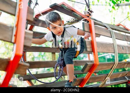 Parcheggio per funi. Il bambino passa l'ostacolo nel parco corda. Foto Stock