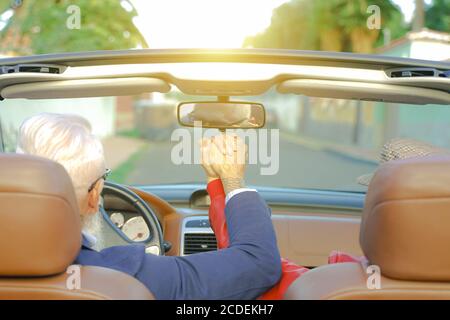 Coppia anziana che tiene le mani mentre si siede insieme in auto. Coppia amorevole che tiene le mani in auto. Primo piano di mani di coppia amorevoli, uomo e donna Foto Stock