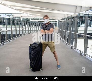 COVID-19 viaggia nella nuova normalità. Viaggiatore con maschera protettiva al terminal dell'aeroporto preoccupato di quarantena di ritorno a casa. Passeggero bloccato in airpo Foto Stock