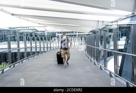 COVID-19 viaggia nella nuova normalità. Viaggiatore con maschera protettiva al terminal dell'aeroporto preoccupato di quarantena di ritorno a casa. Passeggero bloccato in airpo Foto Stock