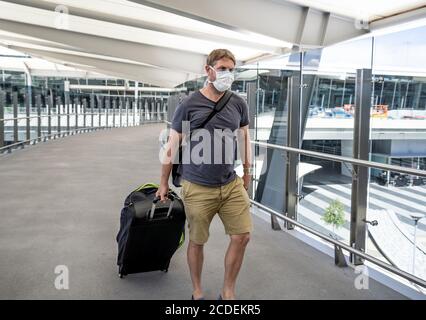 COVID-19 viaggia nella nuova normalità. Viaggiatore con maschera protettiva al terminal dell'aeroporto preoccupato di quarantena di ritorno a casa. Passeggero bloccato in airpo Foto Stock