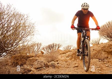 Ciclista in violetta Ridando la Mountain Bike sul sentiero di primavera Enduro. Extreme Sport e Enduro Bike Concept. Foto Stock