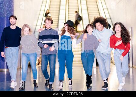 Happy Gruppo di amici che camminano nella stazione metropolitana. I giovani si aspettano per la festa. Gente millenaria sorridente per un jo Foto Stock