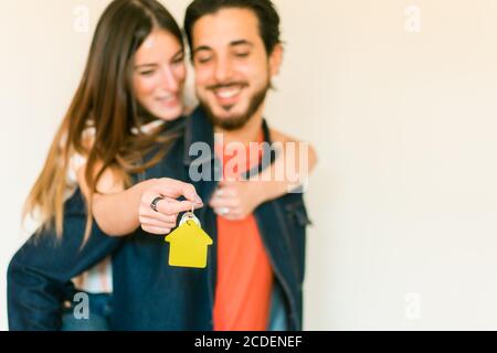 Felice coppia nel nuovo appartamento . La donna ha la chiave per una casa. Chiave con portachiavi a forma di casa. Messa a fuoco a portata di mano - immagine Foto Stock