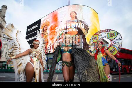 Un trio di ballerini di soca caraibici, Donna Cupid-Thuedi, Andrea Wallace e Fiona Compton, intrattengono i passanti mentre Samsung sveil sul Piccadilly Circus guarda un trailer per il primo Carnevale di Notting Hill digitale di Londra. Foto Stock