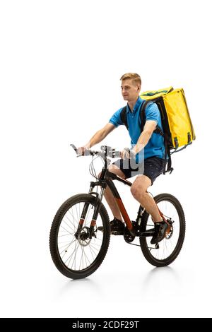 Equitazione. Deliveryman con bicicletta isolata su sfondo bianco studio. Servizio senza contatto durante la quarantena. L'uomo consegna il cibo durante l'isolamento. Sicurezza. Occupazione professionale. CopySpace per l'annuncio. Foto Stock