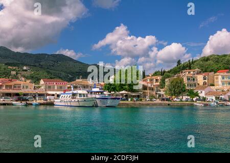 Isola di Corfù/Grecia - 6 maggio 2019: Vista sul bellissimo villaggio di Kassiopi – laguna di mare con acque turchesi calme, barche da crociera, case colorate e la strada Foto Stock