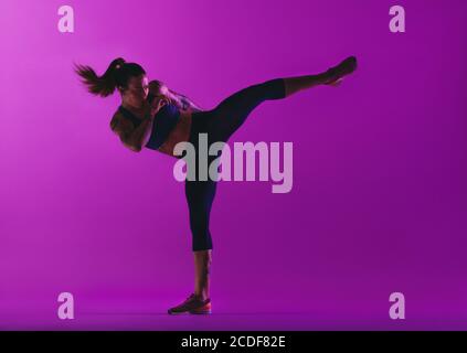 Atleta femminile che fa allenamento fitness. Equilibrio muscolare donna su una gamba che pratica calci. Foto Stock