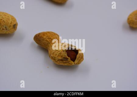 Arachidi naturali nella loro buccia, che si apre in vari modi. Le conchiglie aperte con noci di arachide si trovano su uno sfondo bianco. Foto Stock