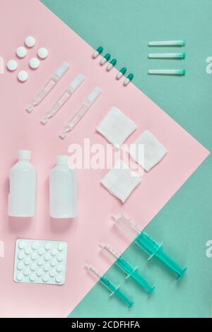 Vista dall'alto compresse, siringhe m diverse medico su cartone colorato, rosa, blu e verde chiaro. Medicinali su cartone colorato di fila. Via superiore Foto Stock