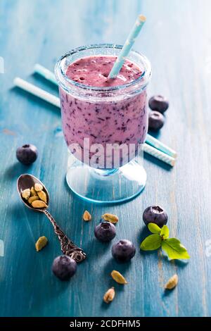 lassi mirtillo sano o bevanda frullato con cardamomo su blu sfondo di legno Foto Stock