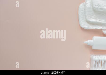 I pannolini per imballaggio in plastica e i tamponi in cotone giacciono su un beige vista di sfondo dall'alto Foto Stock