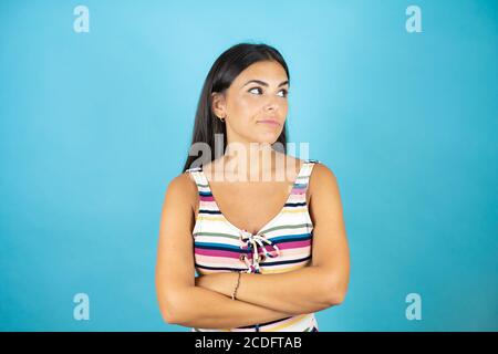 Giovane bella donna che indossa costume da bagno su sfondo blu isolato attraversato braccia guardando la fotocamera molto grave Foto Stock