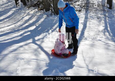 Padre e figlia giocano sulla neve in montagna durante la stagione invernale. Giocare nella neve in inverno. Attività, persone. Foto Stock