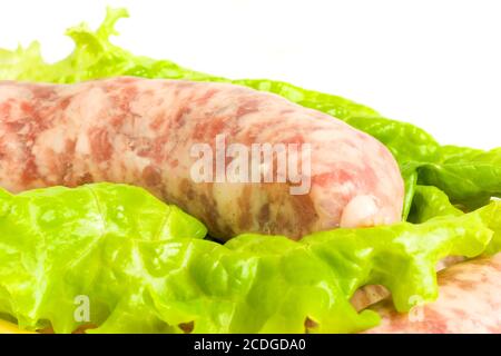 Primo piano di una salsiccia non cotta su foglia di insalata Foto Stock