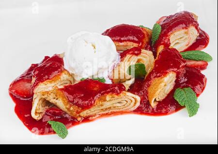 Dessert fatto in casa di frittelle tagliate a pezzetti con scoop di gelato alla vaniglia e foglie di menta isolate su bianco Foto Stock