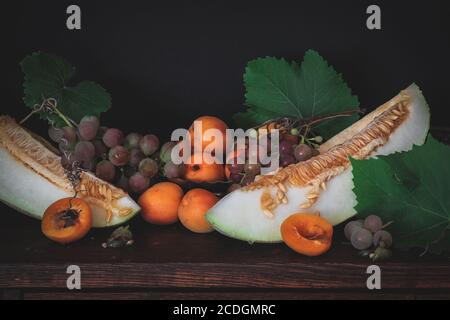 Albicocche, uva e melone a fette in una composizione di natura morta Foto Stock