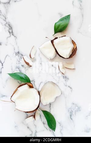 Flatlay con foglie di cocco e verde rotte su sfondo di marmo bianco. Mock up per la pubblicità dei prodotti di bellezza e di salute Foto Stock