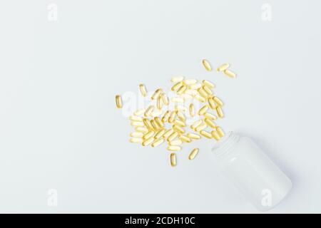 Mucchio di pillole accanto al bicchiere d'acqua sul tavolo bianco, vista dall'alto Foto Stock