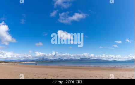 Una vista attraverso Newborough Beach, che mostra uno sfondo delle montagne di Snowdonia, come si vede dal percorso costiero dell'Isola di Anglesey in Galles, Regno Unito. Foto Stock