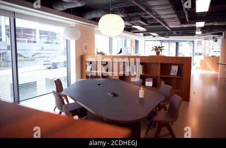 Moderno ufficio vuoto in condivisione con igienizzatore a mano sul tavolo del banco riunioni. Foto Stock