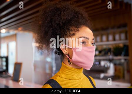 Donna African coffee shop proprietario indossare maschera viso guardando fuori macchina fotografica. Foto Stock