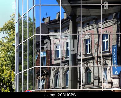 Cracovia. Cracovia. Polonia antichi edifici di affito si riflettono nella facciata di vetro del nuovo edificio per uffici. Foto Stock