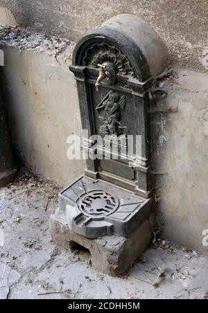 Cracovia. Cracovia. Polonia. Vecchia fontana d'acqua in ghisa con rubinetto nel cortile interno dell'edificio della Città Vecchia. Foto Stock