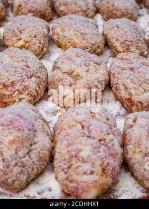 Le cotolette di carne cosparse di farina bianca sul tavolo da cucina. Ricetta culinaria per le cotolette di carne. Cucina cibo. Cucina domestica. Menu di piatti. Taglio bo Foto Stock