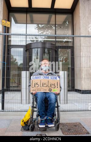 Un uomo si siede su una sedia a rotelle di fronte al Centro Shell, sede centrale di Shell UK Ltd., come parte di una protesta di ribellione per l'estinzione. La campagna di oggi, ‘Lies, Lobying and Greenwashing’, chiede alla Shell di fermare tutte le esplorazioni per nuovi petrolio e gas, e di avviare un processo rapido e continuo per porre fine all’estrazione dei combustibili fossili. Credit: Neil Atkinson/Alamy Live News. Foto Stock