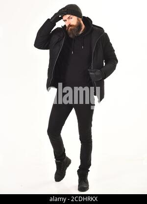 Macho con barba e baffi indossa giacca invernale, guanti e cappello. L'uomo dal volto stretto indossa abiti caldi, isolati su sfondo bianco. Concetto di abbigliamento invernale. Ragazzo in abito nero e brutale. Foto Stock