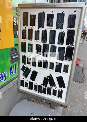 Visualizzazione di schermi di telefoni cellulari incrinati e altri danni al di fuori di un negozio che fissa telefoni cellulari una lucrativa piccola impresa su Manhattan Avenue a Brooklyn, New York. Foto Stock