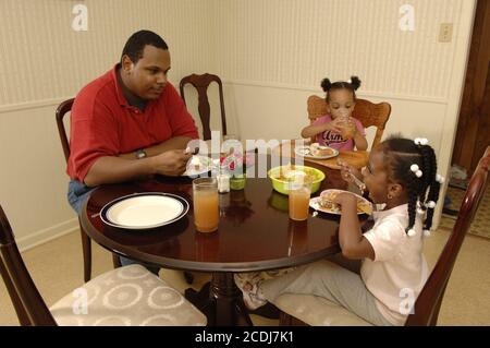 Pine Bluff, AR 16 ottobre 2006: Famiglia afroamericana con bambini piccoli che hanno cena da take-out di cibo messicano a casa. ©Bob Daemmrich Foto Stock