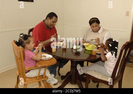 Pine Bluff, AR 16 ottobre 2006: Famiglia afroamericana con bambini piccoli che hanno cena da take-out di cibo messicano a casa. ©Bob Daemmrich Foto Stock