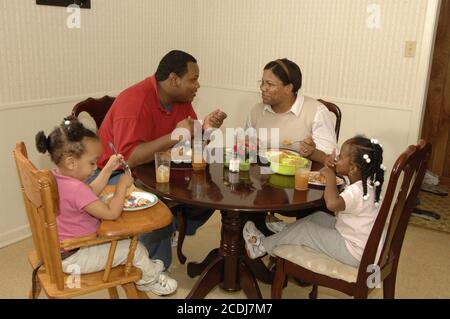 Pine Bluff, AR 16 ottobre 2006: Famiglia afroamericana con bambini piccoli che hanno cena da take-out di cibo messicano a casa. ©Bob Daemmrich Foto Stock