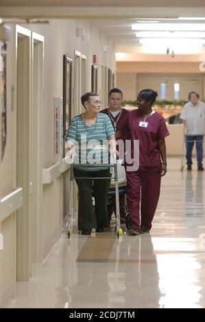 Pine Bluff, AR 16 ottobre 2006: Gli studenti universitari della comunità lavorano in una casa di cura come parte della loro formazione nel campo dell'assistenza sanitaria. Qui, si pratica a guidare un residente senior in modo sicuro lungo un corridoio. Versioni del modello disponibili. ©Bob Daemmrich Foto Stock