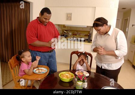 Pine Bluff, AR 16 ottobre 2006: Famiglia afroamericana con bambini piccoli che hanno cena da take-out di cibo messicano a casa. ©Bob Daemmrich Foto Stock