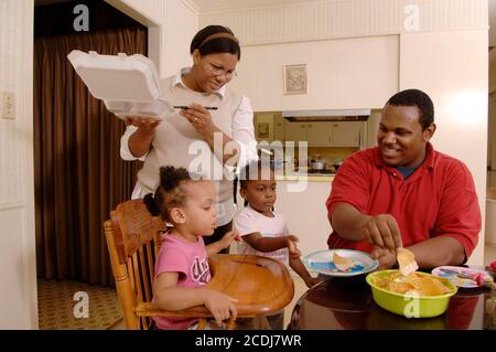 Pine Bluff, AR 16 ottobre 2006: Famiglia afroamericana con bambini piccoli che hanno cena da take-out di cibo messicano a casa. ©Bob Daemmrich Foto Stock