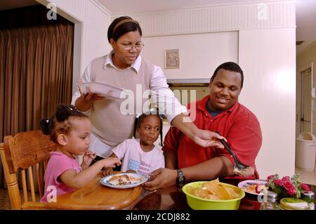 Pine Bluff, AR 16 ottobre 2006: Famiglia afroamericana con bambini piccoli che hanno cena da take-out di cibo messicano a casa. ©Bob Daemmrich Foto Stock