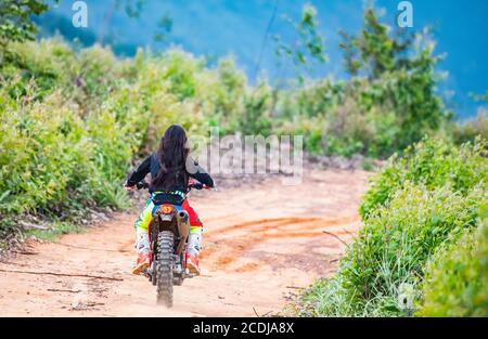 Donna che cavalca la sua bici da terra sulla pista forestale di Pak Chong / Thailandia Foto Stock