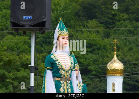 DAKHOVSKY, RUSSIA - LUGLIO 25 2015: Ballerine in costumi tradizionali, montagne adigskih sullo sfondo, e la cupola della chiesa ortodossa Foto Stock