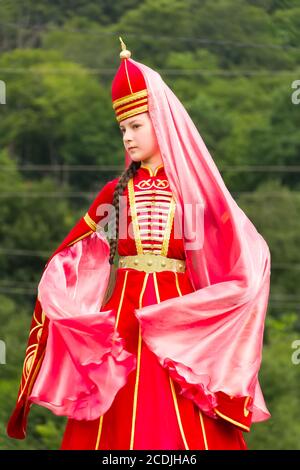 DAKHOVSKY, RUSSIA - LUGLIO 25 2015: La ragazza musulmana in una bella adyghe nazionale rossa contro le montagne. Il Festival 'Lago-Naki: Kunatskaya' Foto Stock