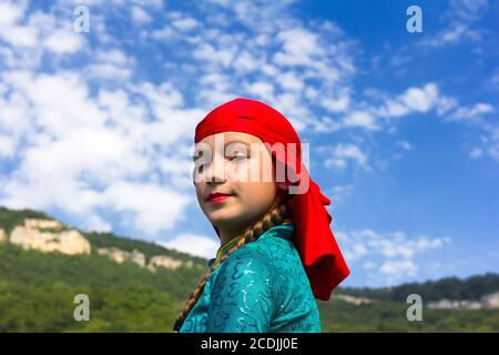 Adygea, RUSSIA - 25 2015 LUGLIO: Ritratto di una giovane ballerina in abito circassiano tradizionale su uno sfondo di cielo e montagne. Festa etnica nel Foto Stock