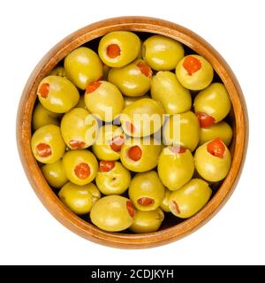 Piccole olive verdi sottaceto, farcite con peperoncino rosso in una ciotola di legno. Frutta di Olea europaea, farcita con fette di peperone. Primo piano. Foto Stock