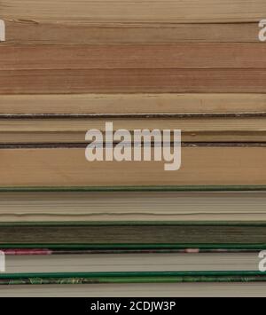 Primo piano del lato di un mucchio di libri con carta ingiallita che crea una forma astratta. Foto Stock