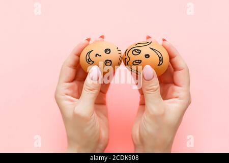 Due uova sorrisano in mano su uno sfondo rosa Foto Stock