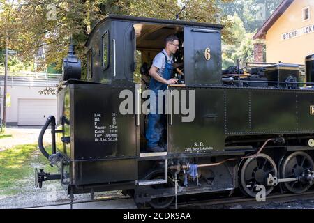 Un conducente si affaccia sul lato di un treno a vapore vecchio stile dal 1914 Klaus n. 6925 sulla ferrovia a scartamento ridotto del Museo Steyr Valley, Austria Foto Stock