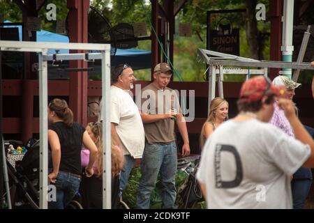 Due agricoltori stanno intrattenendo una conversazione divertente tra la folla di persone durante la fiera annuale di Goshen, Connecticut, USA. Foto Stock