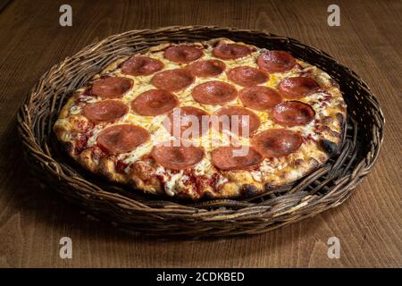 Deliziosa pizza Pepperoni servita su un cesto fatto a mano Foto Stock